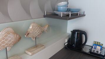 Un comptoir de cuisine avec une machine à café, des sachets de thé et des sculptures de poissons décoratives.