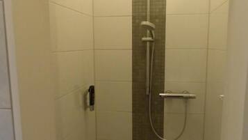 Un box de ducha con pared de azulejos, un cabezal de ducha y un rociador de mano.
