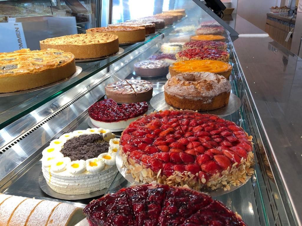 A variety of cakes displayed in a glass case.