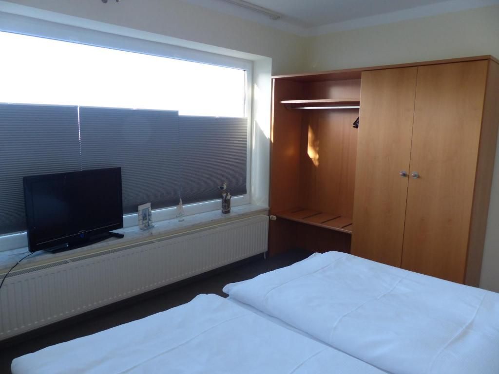 Ein Hotelzimmer mit einem Bett, einem Fernseher, einem Kleiderschrank und einem Fenster mit Jalousien.