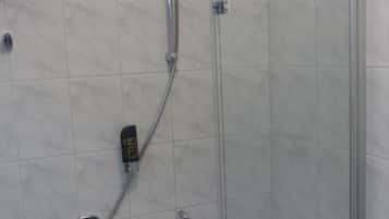 Um chuveiro com box de vidro, com chuveiro manual e torneira manual.