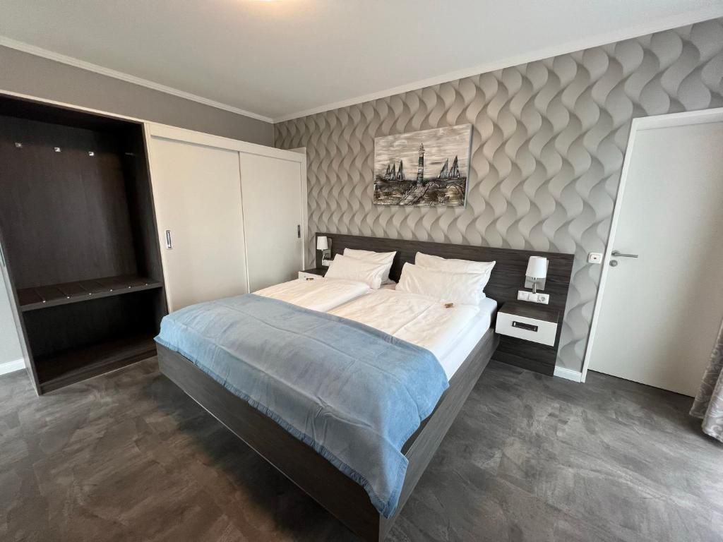 Un dormitorio con cama, armario, mesita de noche y una obra de arte en la pared.