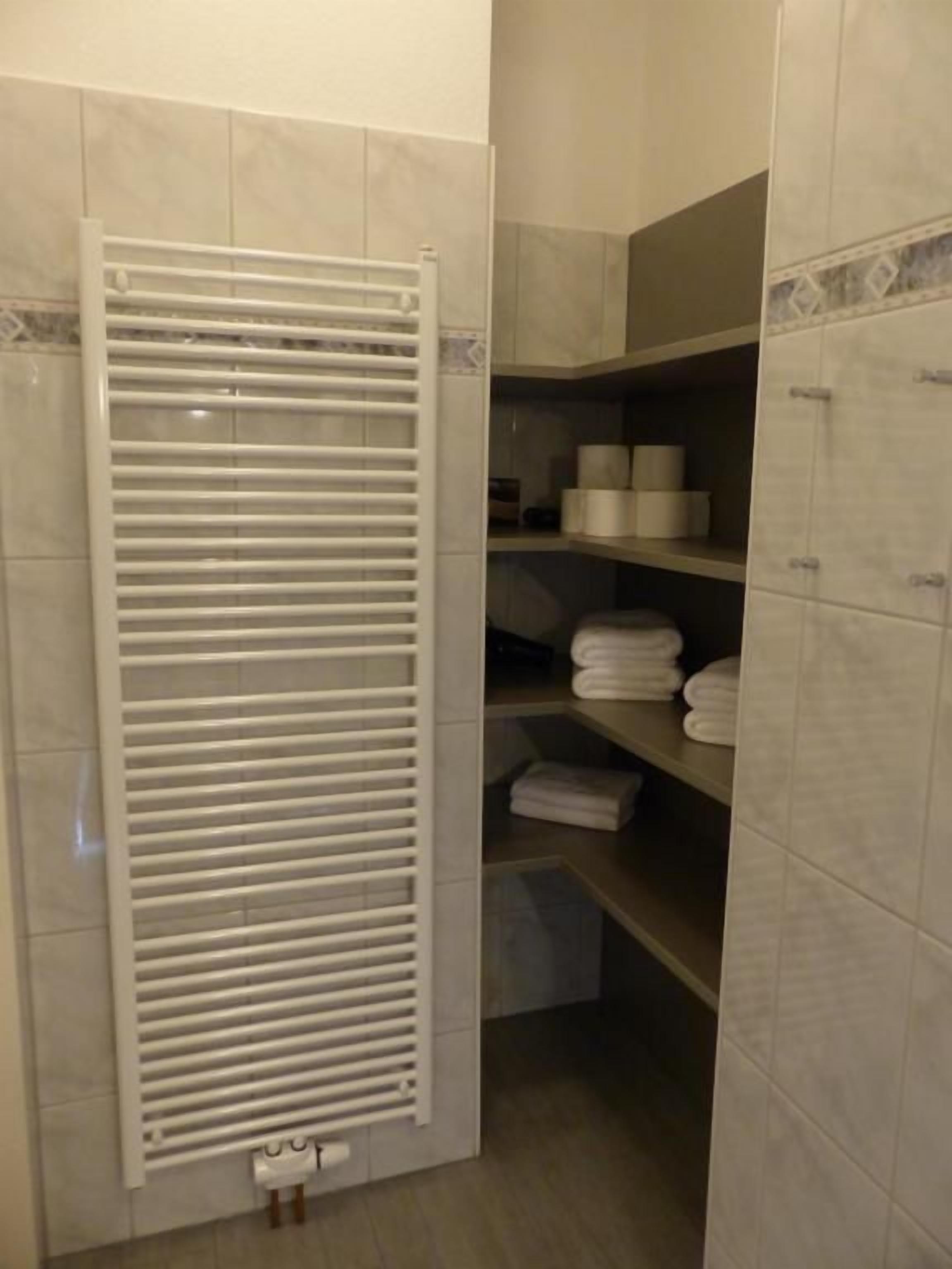 Une salle de bain équipée d’un porte-serviettes, d’étagères avec des serviettes et de toilettes.
