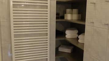 Une salle de bain équipée d’un porte-serviettes, d’étagères avec des serviettes et de toilettes.