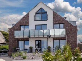 Ein modernes, zweistöckiges Haus mit Balkon, Ziegelaußenwand und großen Fenstern.