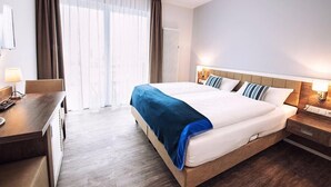 A hotel room with a large bed, a desk, and a window with curtains. - Pension an Bord (Varel)