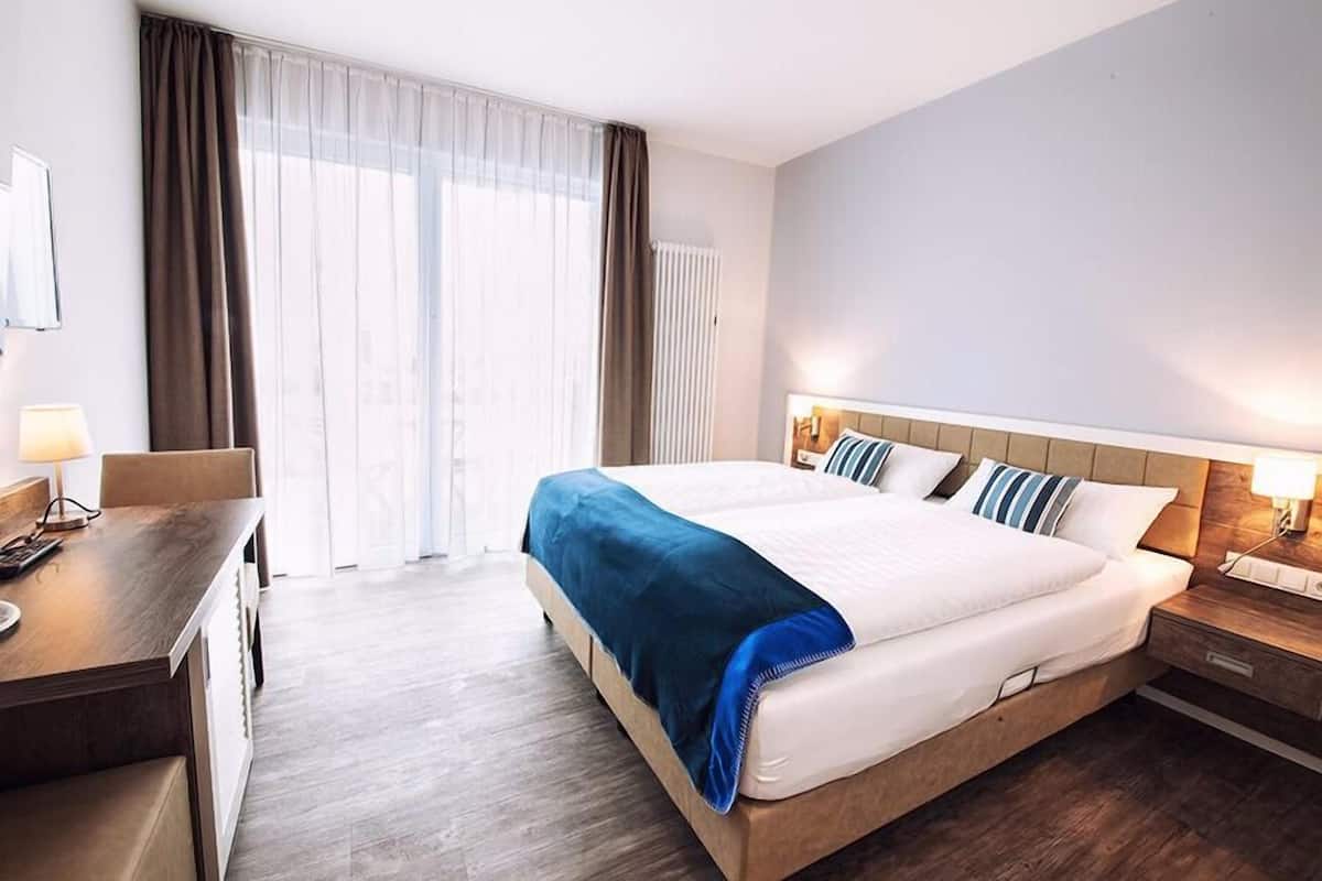 Camera d'albergo con un letto grande, una scrivania e una finestra con tende.