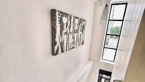A staircase with a modern design, a wall-mounted artwork, and a window with a view of greenery. - Anton's Inn Hotel (Balanga)