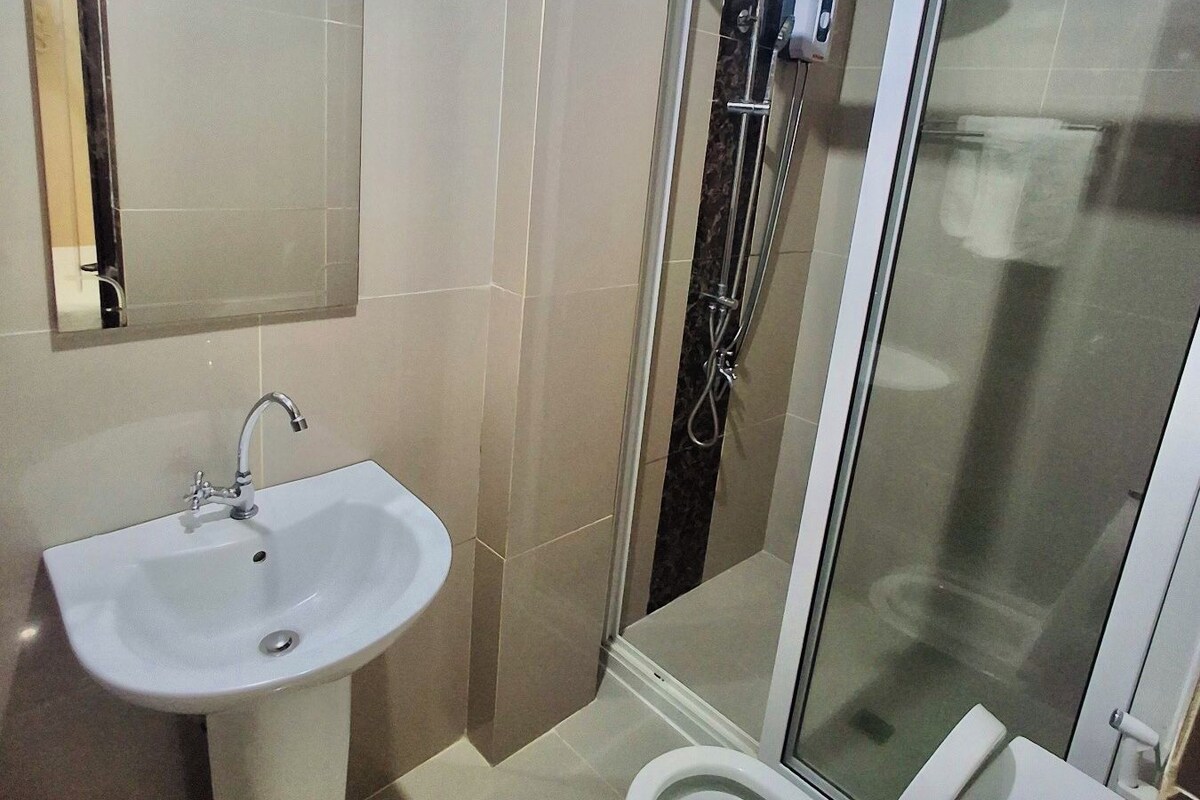 A bathroom with a sink, toilet, and glass-enclosed shower.