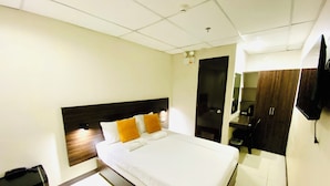 A hotel room with a bed, a desk, a wardrobe, and a television. - Anton's Inn Hotel (Balanga)