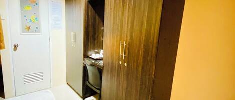 A hallway with a wooden wardrobe, a desk, and a trash bin.