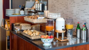 A breakfast buffet with bread, pastries, fruit, and juice dispensers. - Median Hotel Garni (Wernigerode)