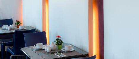 A modern dining area with tables and chairs, decorative wall sconces, and a minimalist decor style.