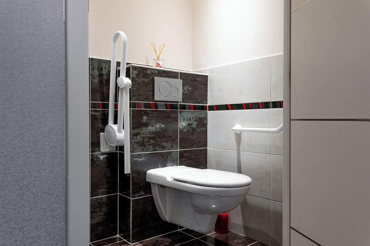 Un baño moderno con inodoro blanco, cabina de ducha con mampara de vidrio y toallero de pared.
