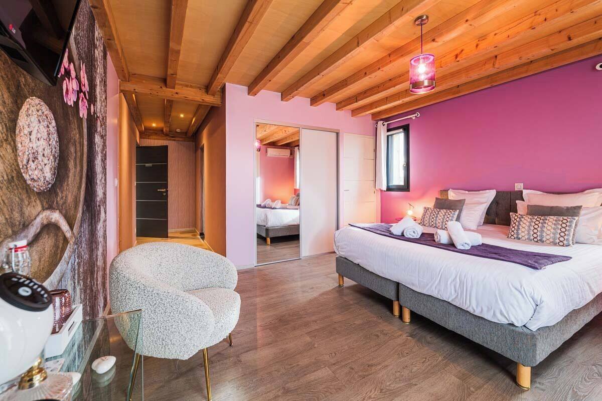 A bedroom with a large bed, a chair, and a wooden ceiling.
