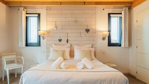 A bedroom with a large bed, two bedside tables, a chair, and two windows with curtains. - Ome Sweet Home (Laubressel)