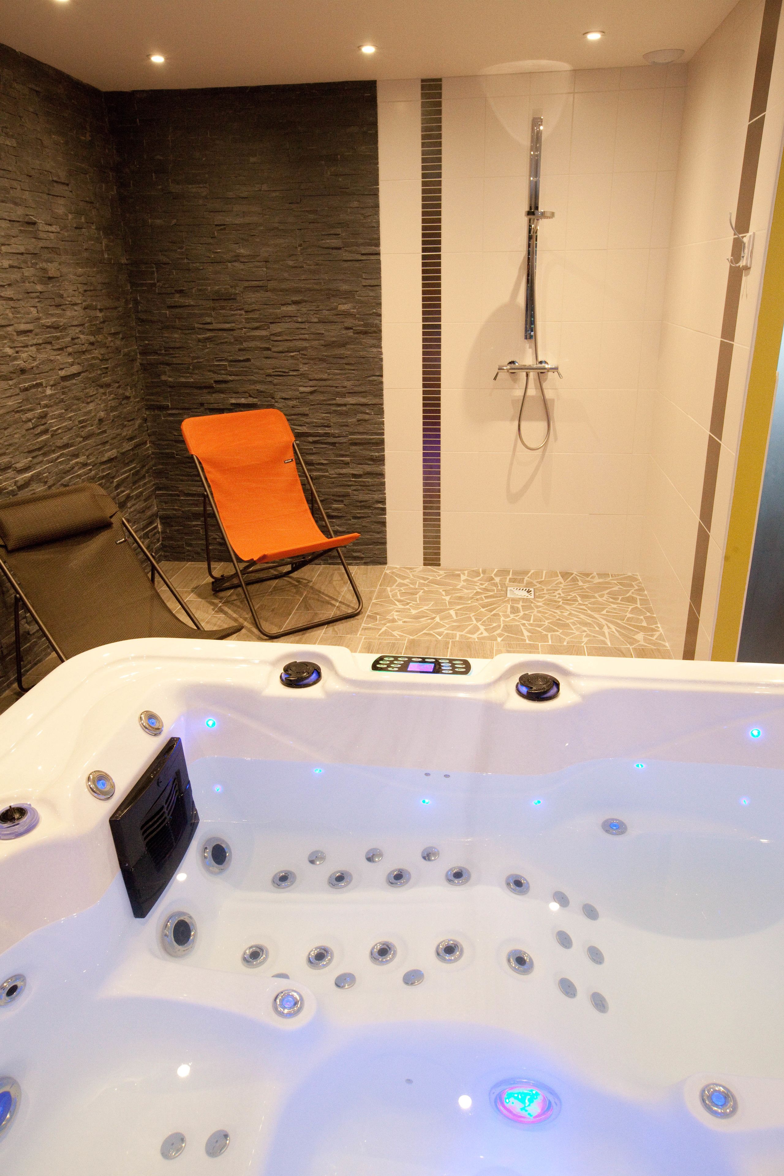 Une salle de spa équipée d’un bain à remous, d’une douche et d’un espace détente.