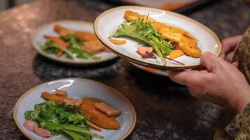 A person holding a plate with food, including breaded chicken and greens, on a table.