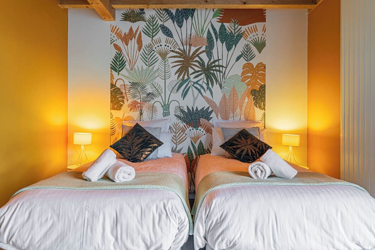 A double room with two beds, each with a pillow and a rolled towel.