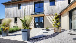 A modern two-story house with a wooden facade, large windows, and a gravel driveway. - Ome Sweet Home (Laubressel)