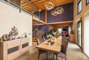 Un amplio comedor con una larga mesa de madera, asientos cómodos e iluminación colgante moderna.