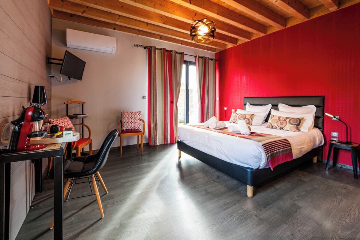 A bedroom with a bed, a desk, a chair, and a TV.