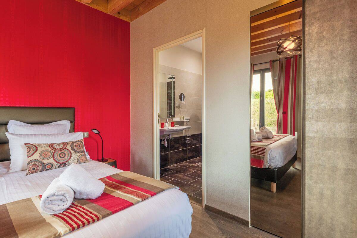 A hotel room with a large bed, a bathroom with a shower, and a view of the outdoors.