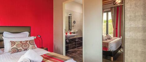 A hotel room with a large bed, a bathroom with a shower, and a view of the outdoors.