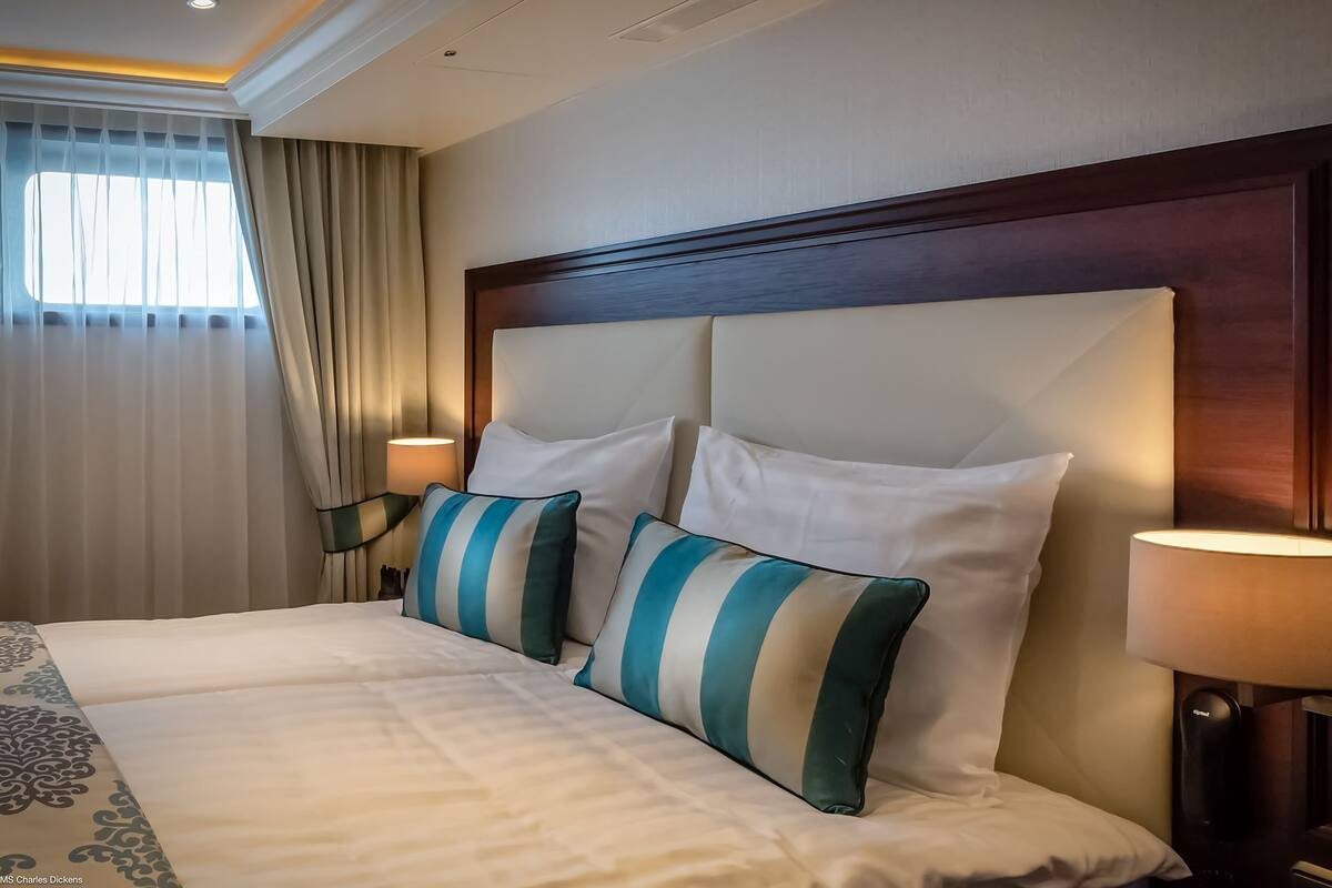 Habitación de hotel con una cama grande, dos lámparas de noche y una ventana con cortinas.