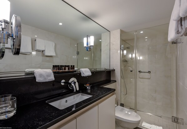 Un baño moderno con encimera negra, cabina de ducha de vidrio y inodoro blanco.