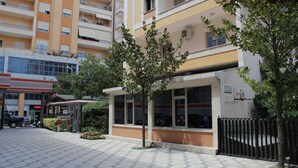 A building with a flat facade, large windows, and a gated entrance. - Hotel International (Fier)