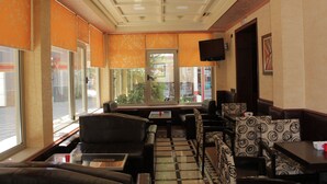 A hotel lobby with a checkered floor, leather seating, and large windows. - Hotel International (Fier)