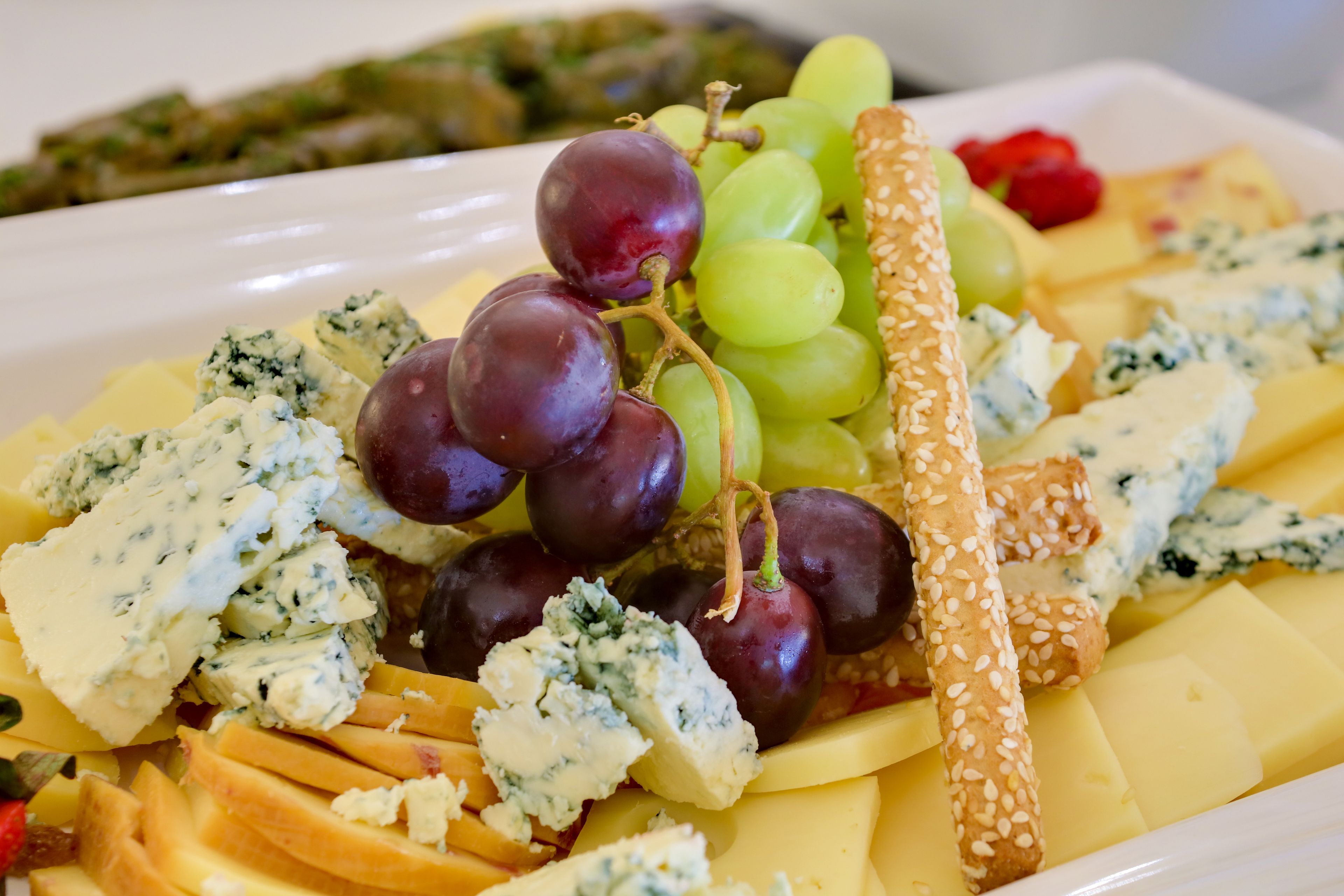 Une planche de charcuterie avec divers fromages, des raisins et des crackers.