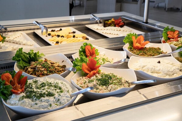 A buffet with various dishes including salads, dips, and garnished items. - Olympian Bay Grand Resort by Anayia All Inclusive Resorts (Dio-Olympos)