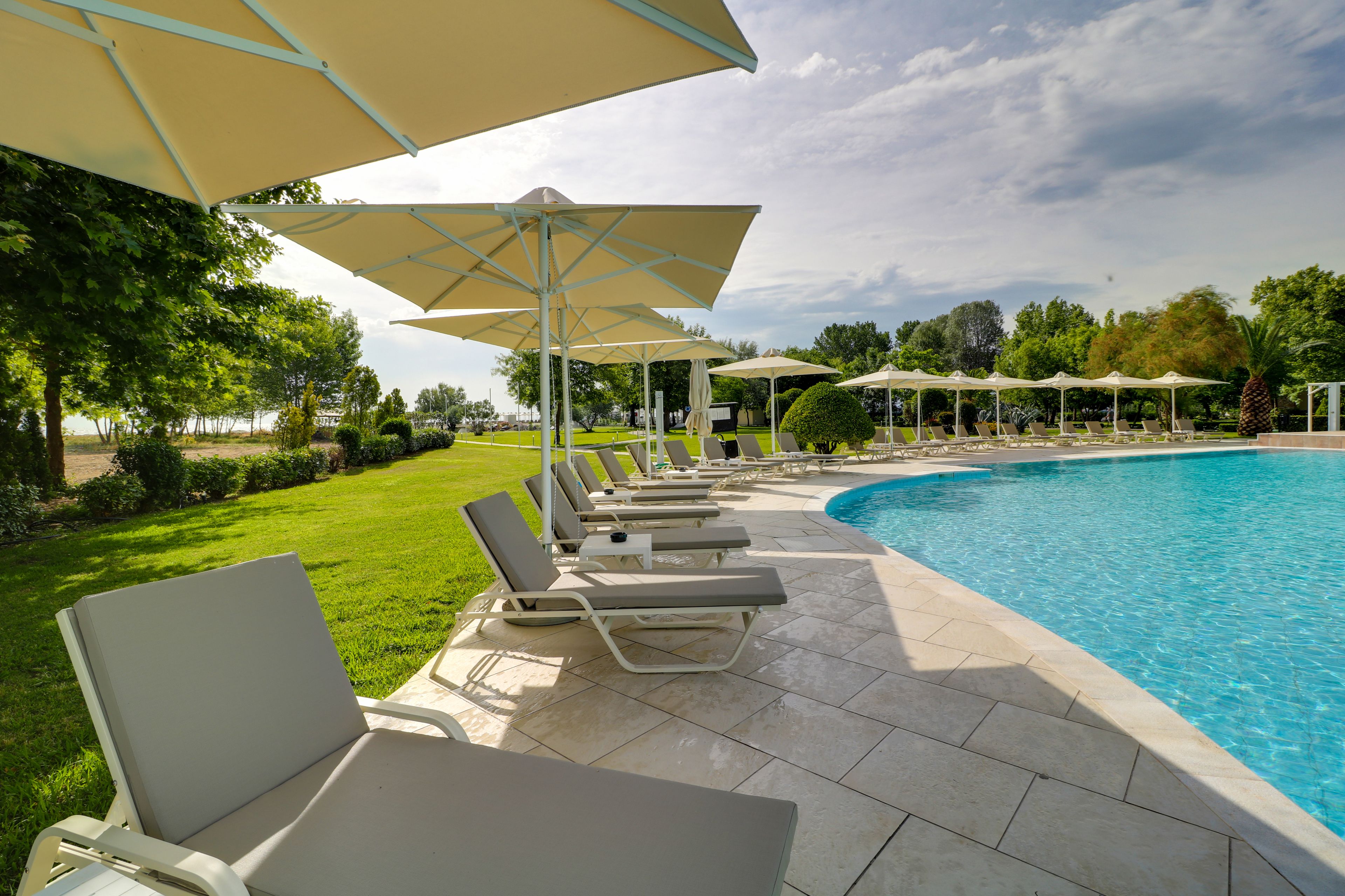 Uma área de piscina com espreguiçadeiras e guarda-sóis.