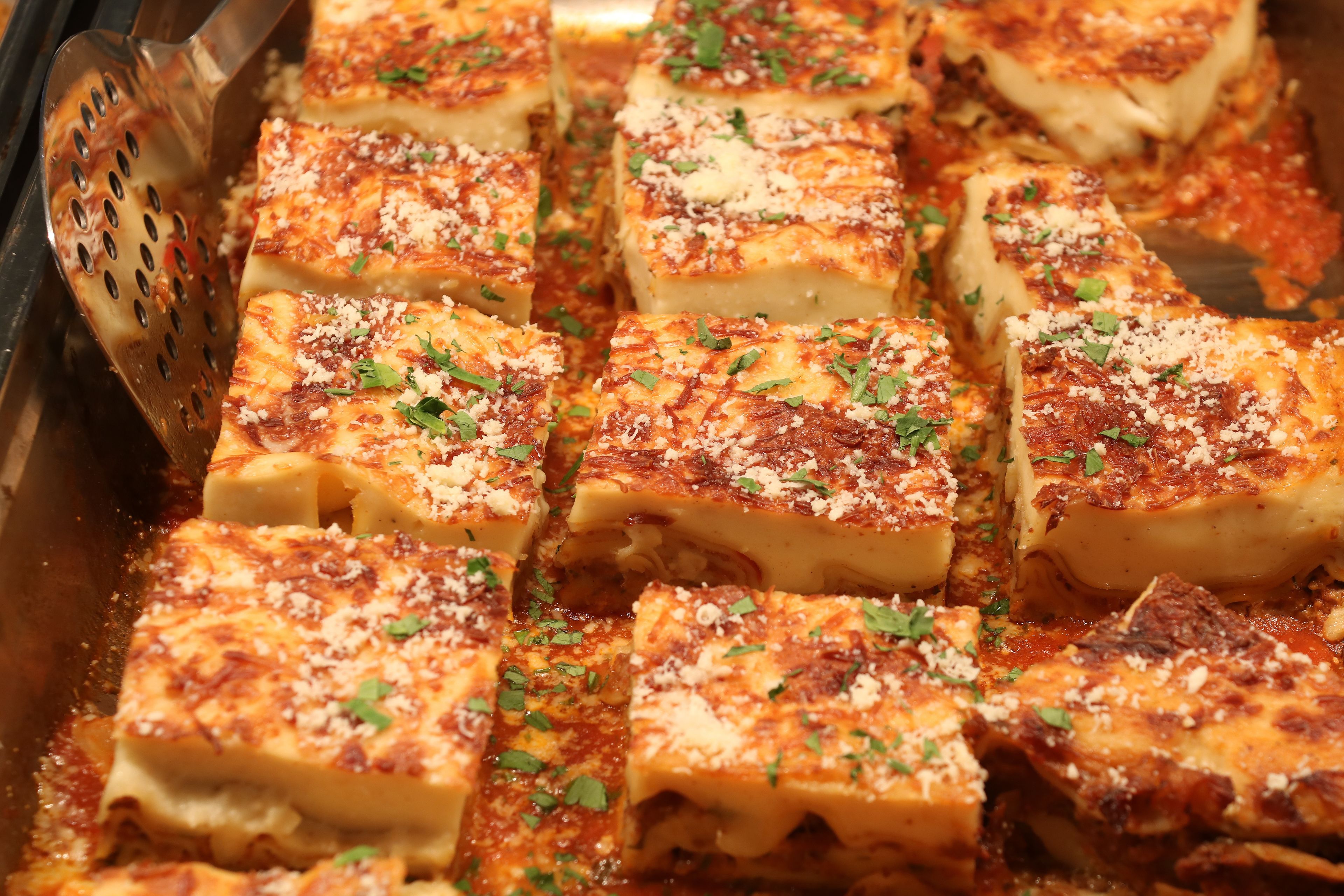 A tray of baked lasagna with cheese and herbs.