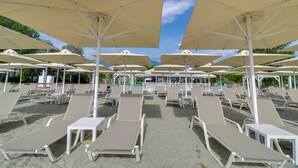 Une plage bordée de rangées de chaises longues et de grands parasols.