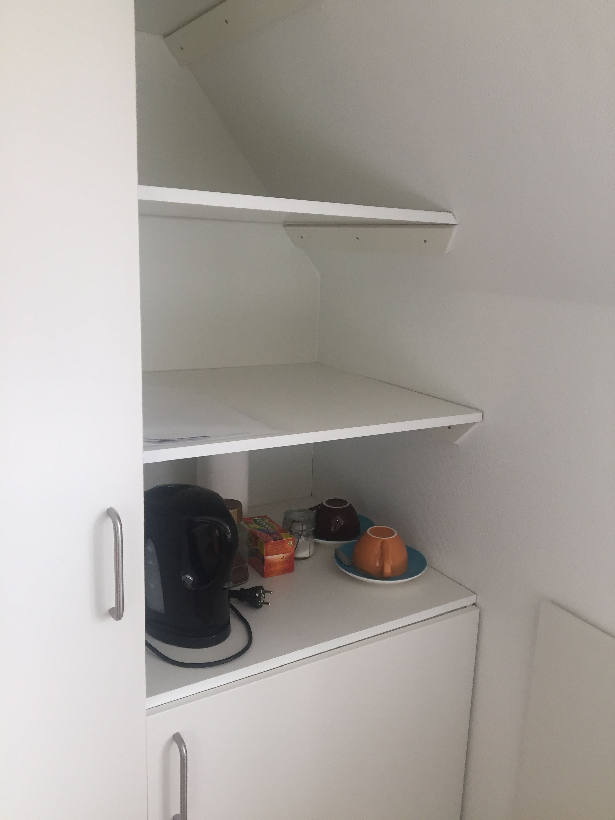 Eine Küchenzeile mit Kaffeemaschine, Wasserkocher und einigen Tassen auf der Arbeitsfläche.