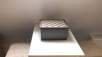 A small room with a white table, a chessboard, and a bench with floral upholstery.