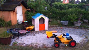 A backyard with a playhouse, a small shed, and various toys.
