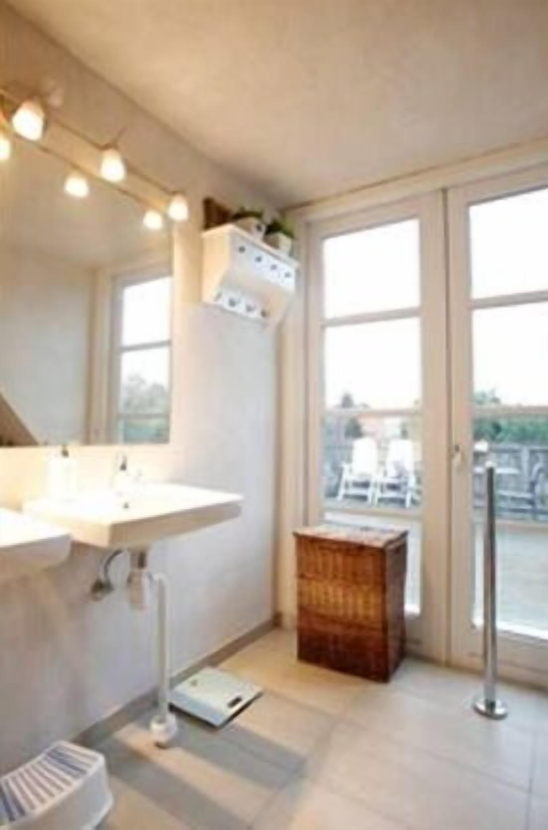 A bathroom with a large window, a sink, and a wooden box.