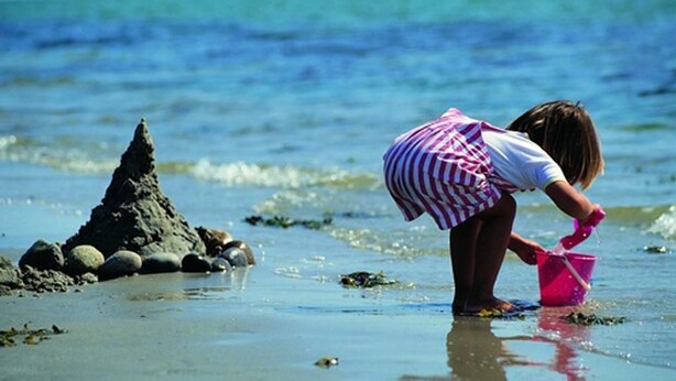 A child playing on a beach with a pink bucket. - Køge Bed & Kitchen (Koge)
