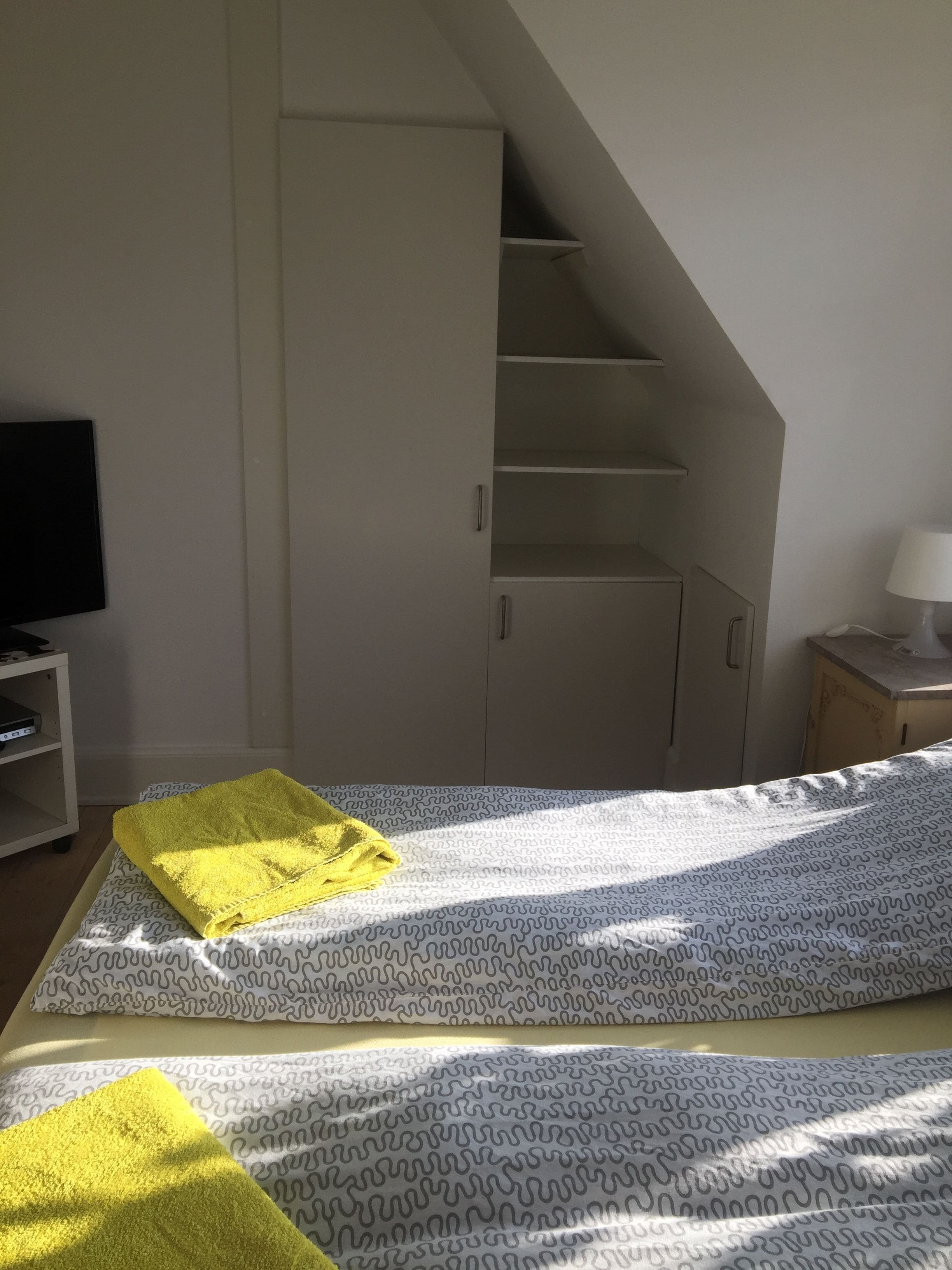 A bedroom with a bed, a TV, a lamp, and a staircase.
