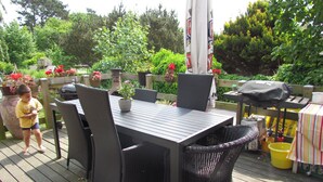 An outdoor patio with a table and chairs, surrounded by potted plants and a wooden fence. - Køge Bed & Kitchen (Koge)