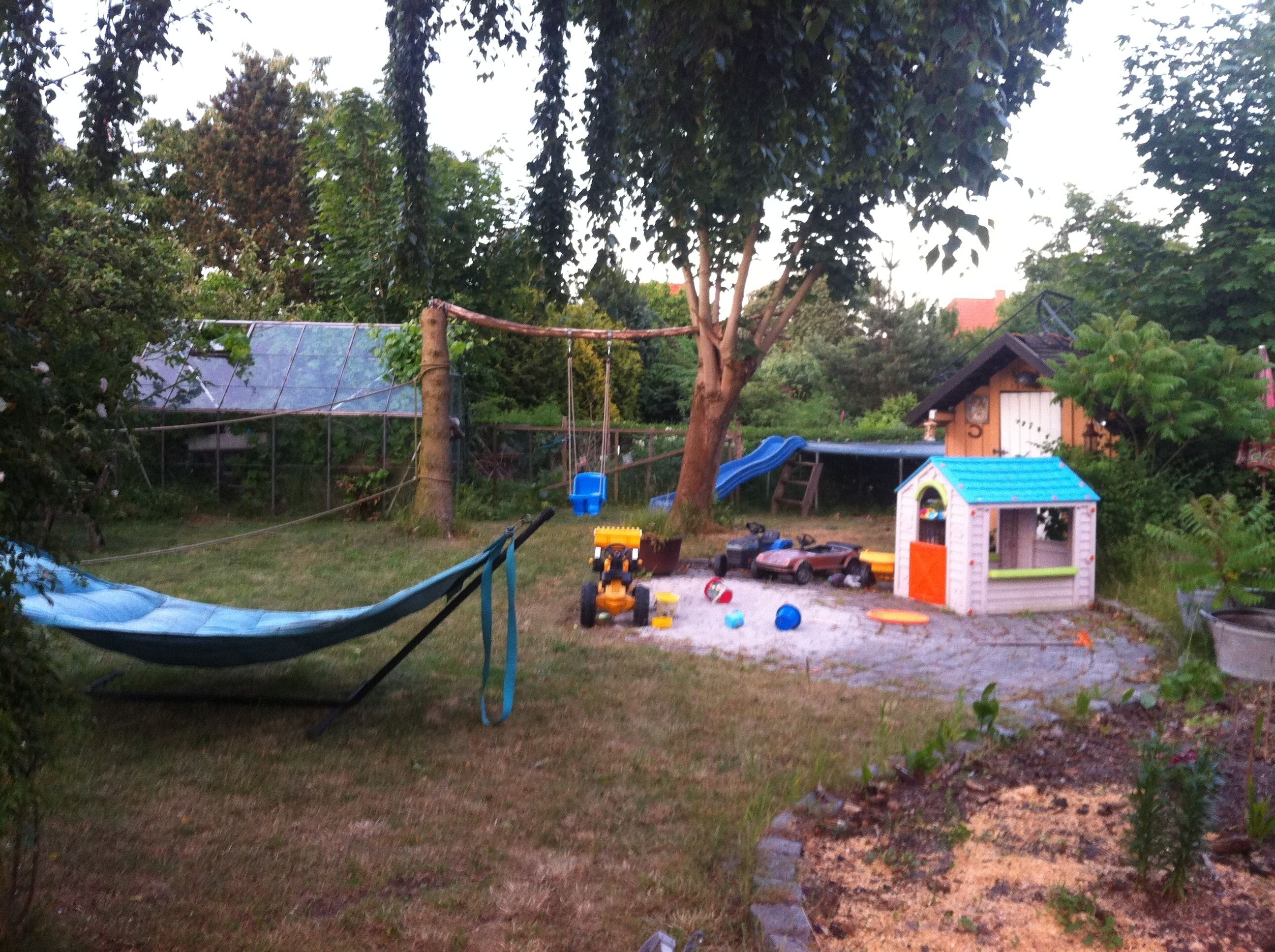 A backyard with a hammock, a playhouse, and a swing set.