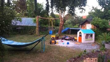 A backyard with a hammock, a playhouse, and a swing set.
