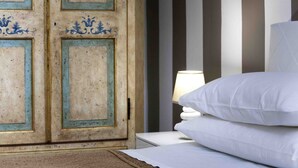 A bed with white bedding and a lamp on a bedside table. - Vanna Home (Sorrento)