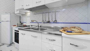 A modern kitchen with white cabinets, stainless steel appliances, and a tiled backsplash. - Vanna Home (Sorrento)