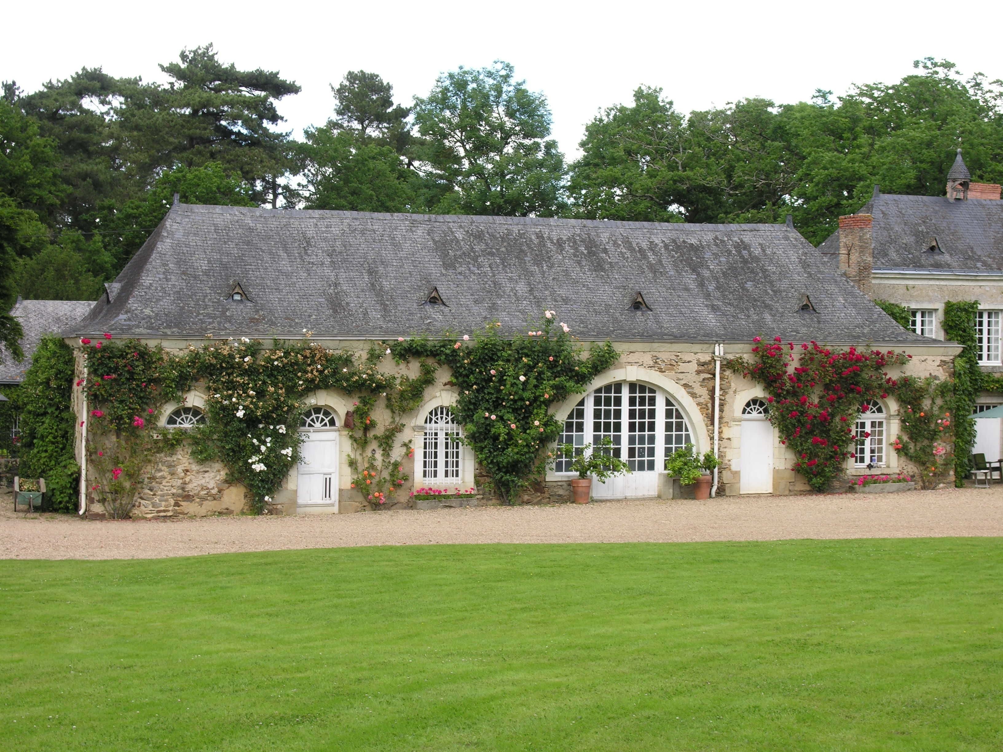 A stone building with arched windows and a sloped roof, surrounded by a well-maintained lawn.