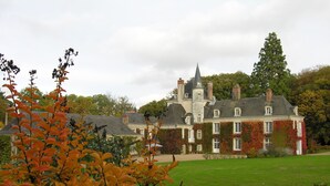 A large, historic building with a prominent tower, surrounded by a well-maintained lawn and autumn foliage. - Château du Plessis - Anjou (La Jaille-Yvon)